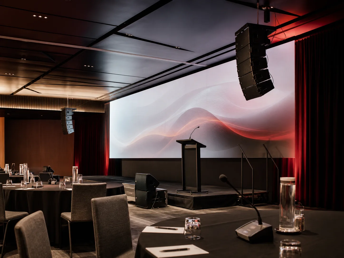 Commercial event room with a projection screen, lectern, stage and loudspeakers