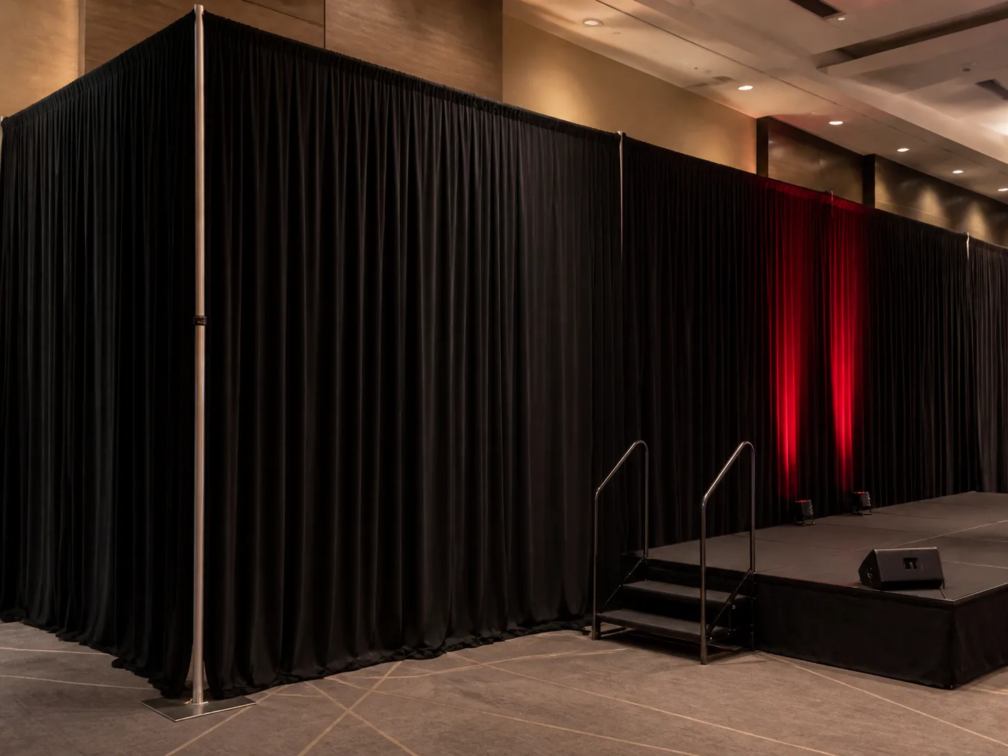 Black event drape beside a stage with red uplighting