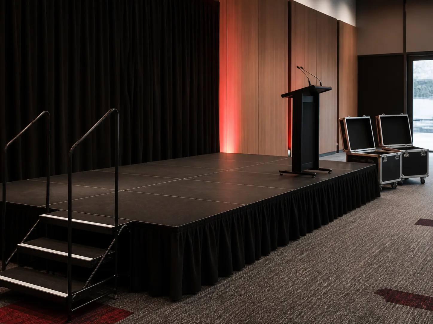 Raised event stage with a lectern, stairs and road cases